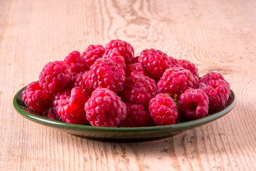 Raspberries on a plate and a wooden table