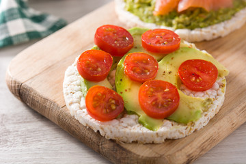 Puffed rice cake with tomatoes and avocado on wooden table	