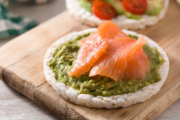 Puffed rice cake with guacamole and salmon on wooden table