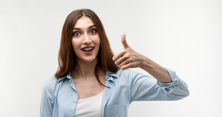 Happy caucasian Young female with long chestnut hair shows OKAY sign with both hands, demonstrates approval