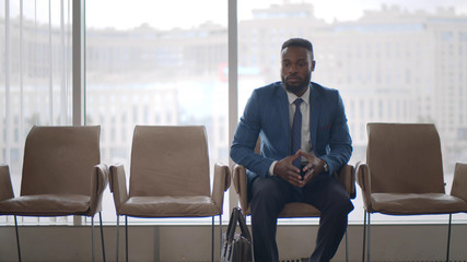 Handsome african man checking time while waiting for job interview