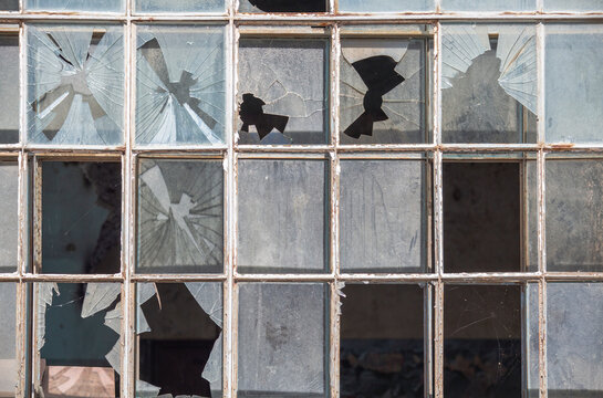 Old window frame of industrial building with broken glass