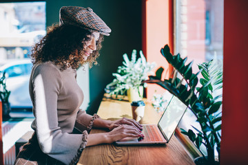 Positive female copywriter wear in cap watching funny videos after working on laptop device, trendy...