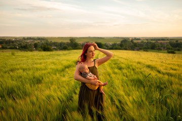 A mother tenderly holds her three month old son in her arms in a wheat field.