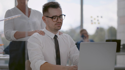 Female masseur massaging tired employee shoulders at workplace