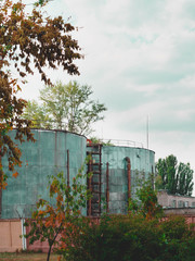 Two industrial tanks surrounded by lush greenery