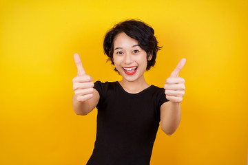 Good job! Portrait of a happy smiling blue eyed young successful woman giving two thumbs up gesture standing indoors. Positive human emotion facial expression body language. Funny girl