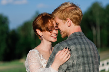 Fototapeta premium Nice redhead young just married happy couple kissing in the sunset outdoors