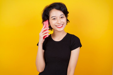 Portrait of a smiling young casual brunette woman talking on mobile phone isolated over white background.
