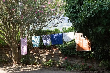 Colored clothes hanging on a wire with clothespins in the garden (Pesaro, Italy, Europe)