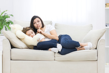Fototapeta premium Photo of little girl sleeping and her mother showing silence sign.