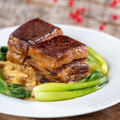 Dong Po Rou (Dongpo pork meat) in a beautiful blue plate with green broccoli vegetable, traditional festive food for Chinese new year cuisine meal, close up.