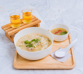 Porridge is placed on a wooden tray and there are two tea glasses. Breakfast