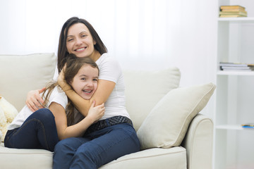 Cute little daughter and her beautiful young mother are playing.