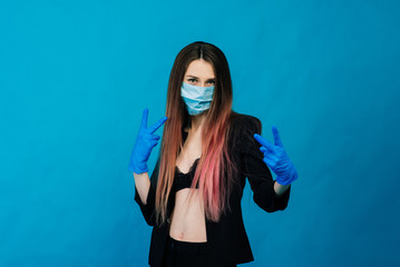 Cheerful and joyful young female playing with protective medical mask and gloves on blue background. Close-up portrait. End of coronavirus quarantine.