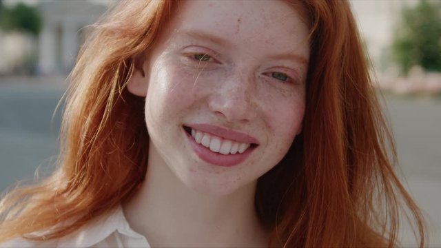 Cute carefree ginger girl with beautiful hair and freckles showing beautiful happy smile at camera enjoying summertime staying outside. Portraits. Females.