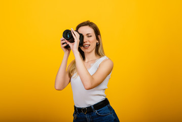 Excited female photographer working in studio. Portrait of stunning blonde girl with photo camera.