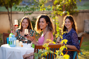 Portrait of three young women posing on the backyard. Young people enjoying harvest time together.