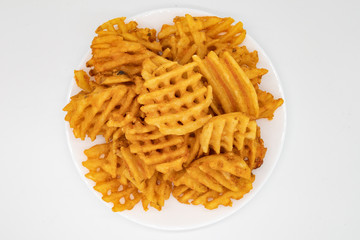 Overhead View of a Large Pile of Waffle Fries on a White Plate with a White Background
