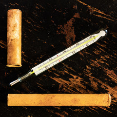 old medical mercury thermometer and paper case on black grunge wood background close-up view from...