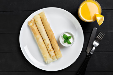 Russian pancakes served in rolls with sour cream
