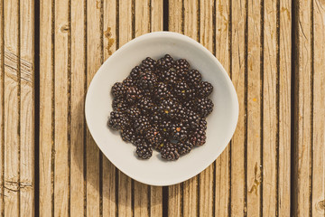 weiße Schale mit frischen Brombeeren auf Holz