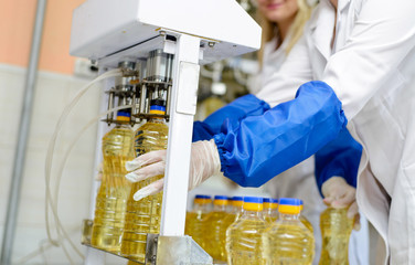 line of production of refined sunflower oil. Girl worker at a factory on a conveyor background with...