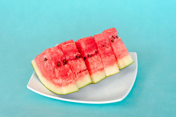 Water melon slices on a plate on blue background