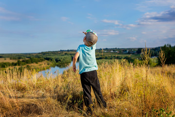 The child looks up to the sky. Boy, summer, landscape, nature, river.