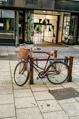 Fototapeta na wymiar A retro style bicycle with a basket on the handle bars locked to an outdoor bike rack in the city centre of Norwich, Norfolk