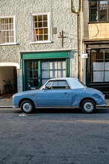 A classic and vintage small  blue car with a white roof parked down a quie t side street in the city of Norwich, Norfolk