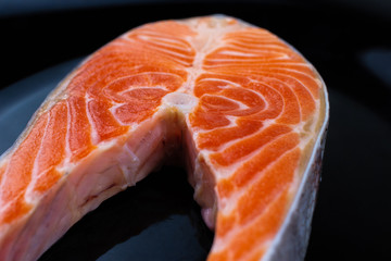 raw salmon steak on a black plate
