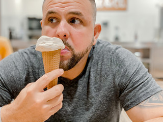 40 year old grown man eating ice cream gelato cone in a icecream shop 