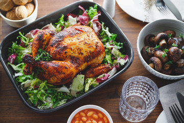 Decorated festive table with whole roasted chicken, salad, pumpkin, mushrooms, beans and walnut. The concept of family dinner or Thanksgiving celebrate