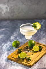 Margarita cocktail with lime and ice on minton light gray concrete table with amazing backlight, copy space. Classic Margarita or Daiquiry Cocktail.