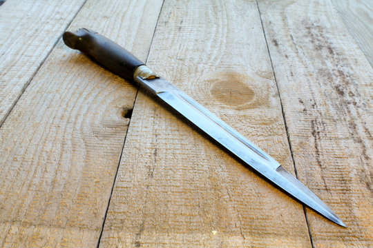 ein altes Messer liegt auf Holzbretter