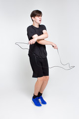 A young boy in a black sports t-shirt and shorts, practicing jumping rope