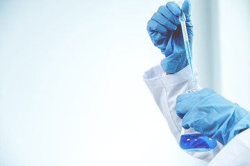 Scientists hold the pipette and drop the blue chemical liquid for research and analysis in a laboratory