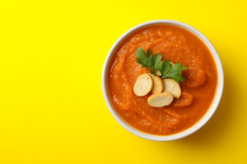 Bowl of pumpkin puree on yellow background, top view