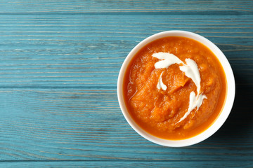 Bowl of pumpkin puree on wooden background, top view