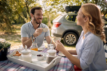 Couple enjoying at countryside and drinking coffee together. Beautiful picnic day