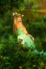 Portrait of a beautiful girl at sunset. Beautiful girl in a green dress. The smile of a forest nymph.