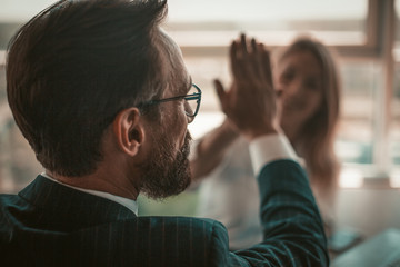 Positive project managers celebrate successful deal. Enthusiastic business people giving five each other in sign of good job and hands solidarity. American spirit concept. Close up shot. Tinted image.