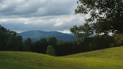 Obraz premium Colorful clouds above the beautiful Blue Ridge Mountains with a green meadow in the foreground