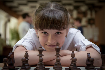 The girl plays chess. Figures on a chessboard. Game of chess.
