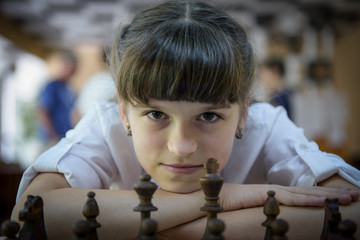 The girl plays chess. Figures on a chessboard. Game of chess.