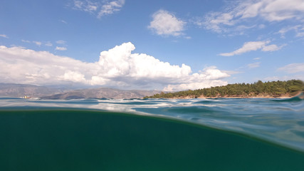 Split underwater photo of exotic Caribbean island seascape with emerald sea and beautiful clouds