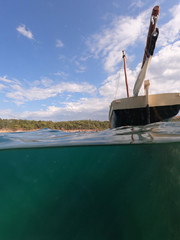 Underwater split photo of traditional classic wooden fishing boat anchored in tropical exotic...