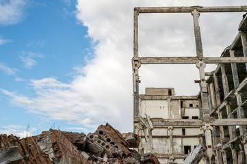 A pile of construction debris and a destroyed frame of a building made of concrete beams against a...
