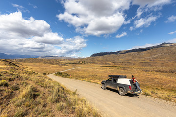Naklejka premium Driving on the road, tourists cross the chacabuco valley national park in solitude aboard a car equipped with a tent.